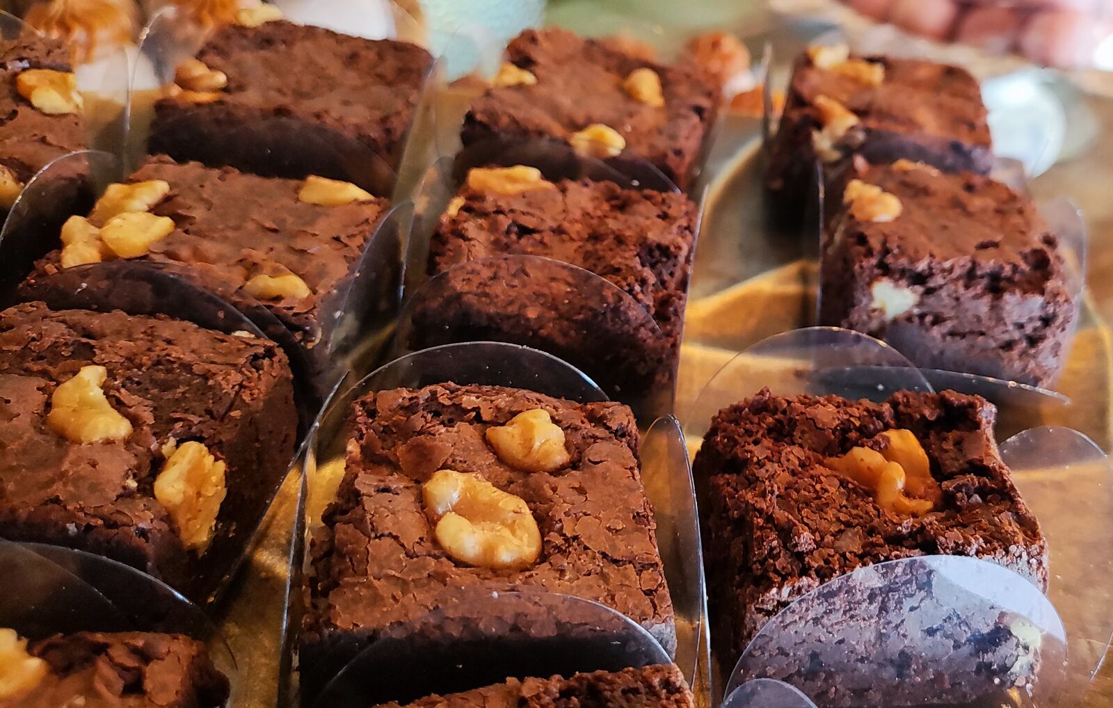 Mini brownies com nozes em forminhas de pétala na mesa de doces de um casamento